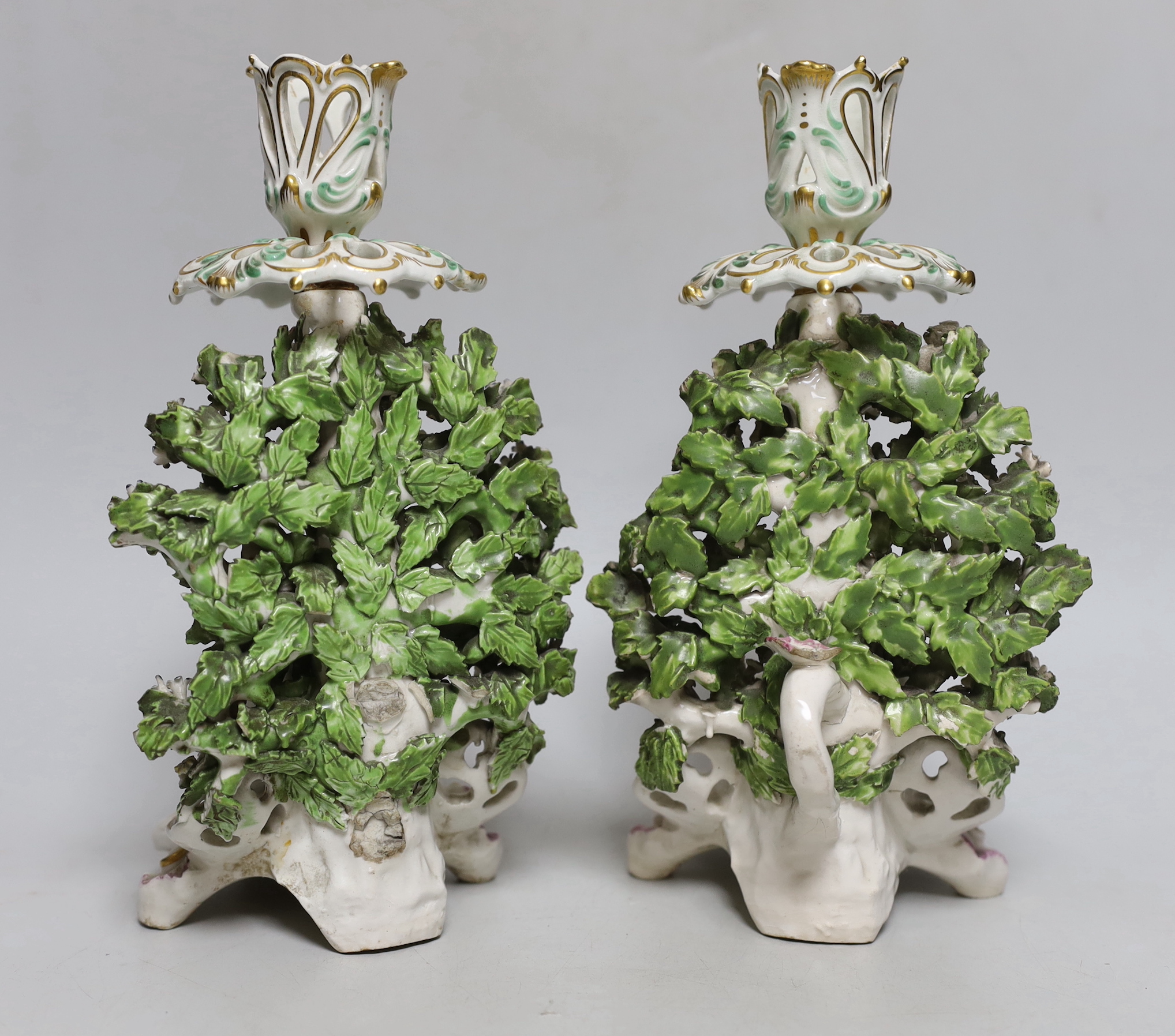 A good pair of Derby candlestick figures of rabbits before a brocage, the elaborate sconce highlighted in green and gold, 23cm high